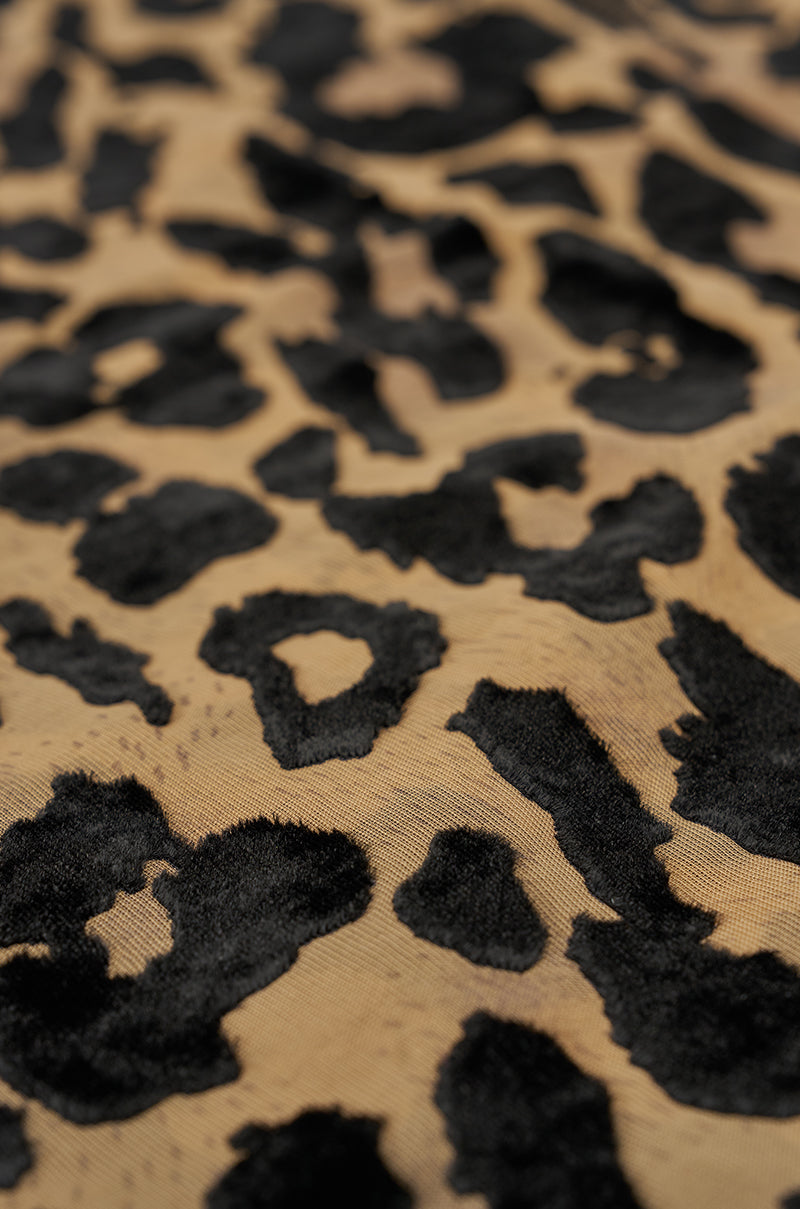 Close-up of the TAKE ME TO ITALY HEADSCARF, showcasing its leopard print fabric with irregular black spots on a tan background—ideal for versatile styling. 2