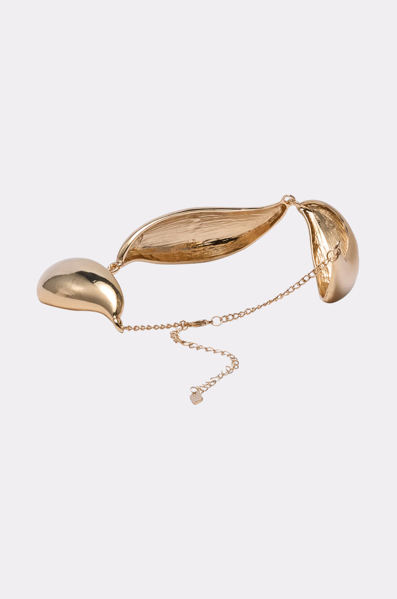 The SUSU NECKLACE features three smooth, gold-tone leaf-shaped segments linked by a delicate chain and clasp, shown on a plain light background. Ideal for pairing with your favorite sculptural statement necklace. 2
