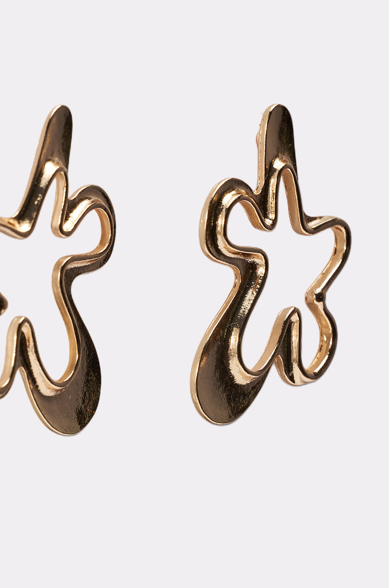 The VIC EARRING features abstract gold-tone designs resembling irregular flowers or stars, partially visible against a plain light background. 3
