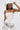 A woman stylishly poses, adjusting the TEST MY LUCK HORSESHOE HAT—a Western hat adorned with rhinestone fringe and a bold horseshoe emblem—while wearing a strapless white dress with metallic details.