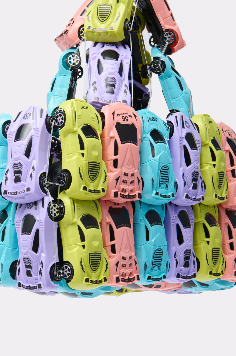 Dozens of pastel toy cars in pink, yellow, purple, and blue are stacked in a triangular pyramid against a white backdrop—an eye-catching scene reminiscent of the playful design of the VROOM CAR PURSE.