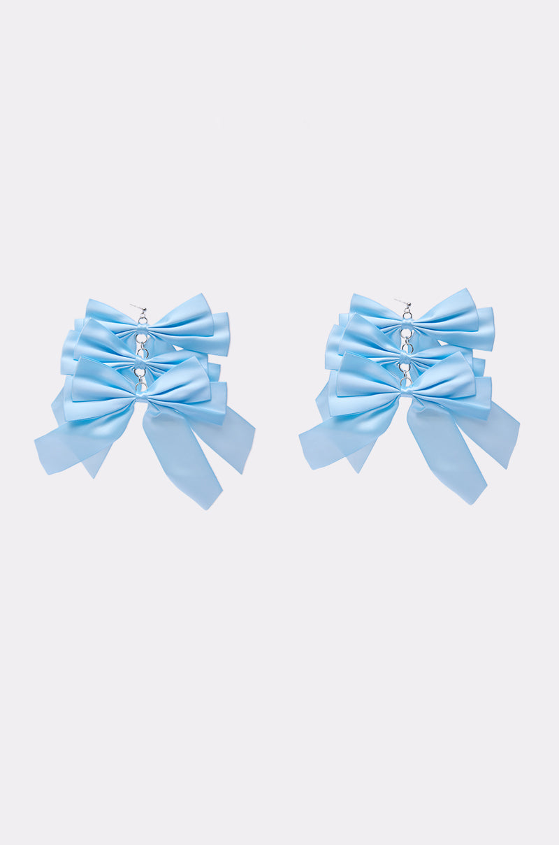 The ULTIMATE FEMME EARRING features two light blue satin bows, each accented with three small center crystals. Displayed on a plain white background, these earrings add a charming and delicate touch to any outfit. 1