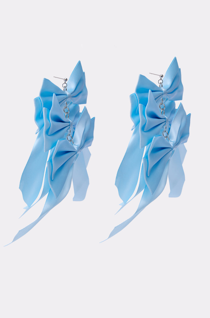 The ULTIMATE FEMME EARRING showcases multiple layered light blue satin bows linked by silver chains, creating a bold statement piece. Displayed on a plain white background. 2