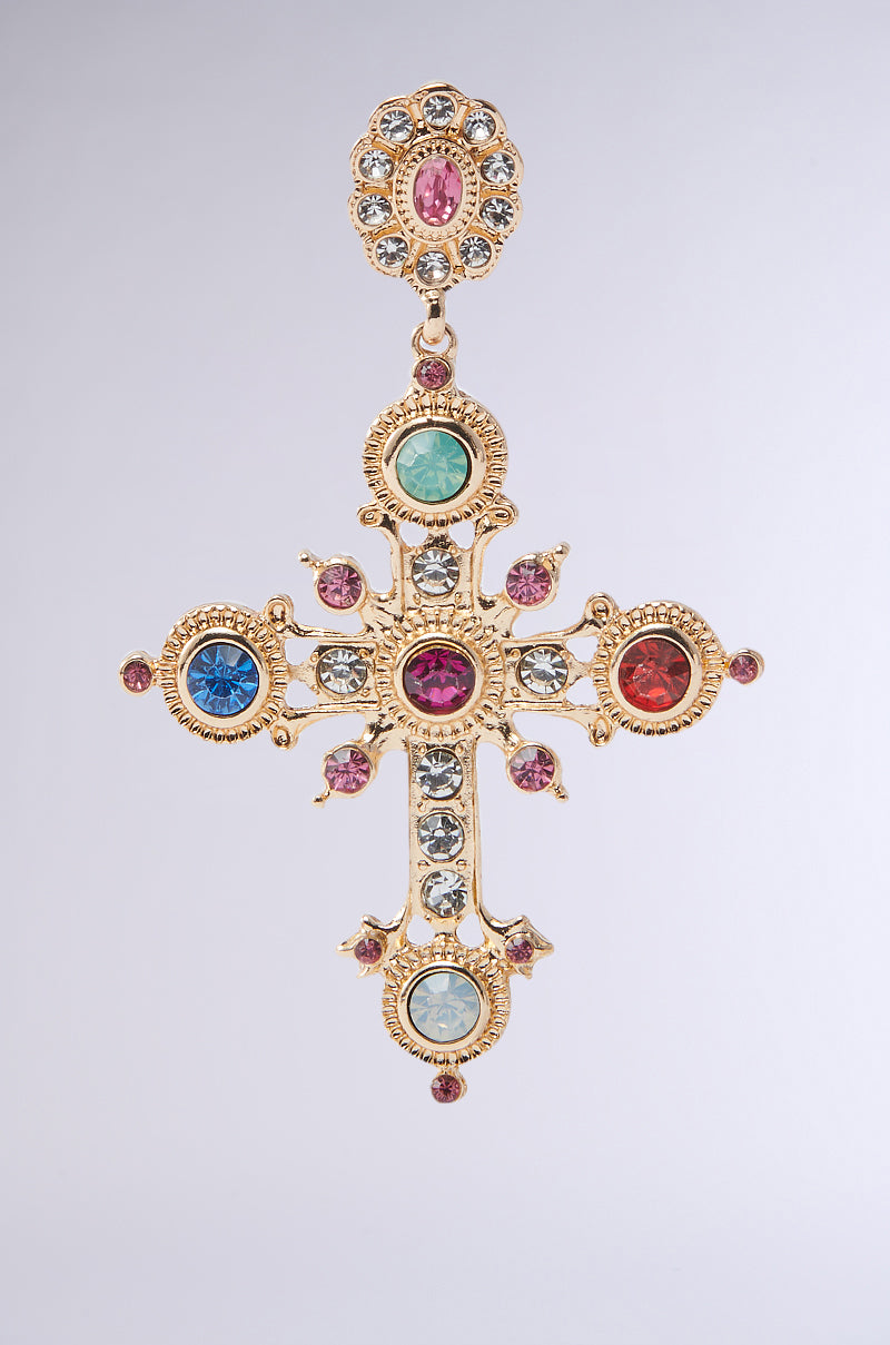 The YOUR MAJESTY EARRING boasts an intricate gold cross design, embellished with red, blue, and green rhinestone-studded gemstones. The symmetrical pattern features detailed motifs and a floral top element against a plain white background.