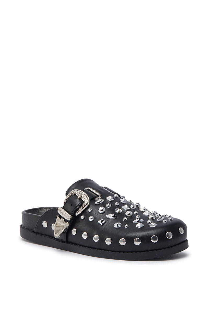 The AZALEA WANG TURIN BLACK METAL EMBELLISHMENT FLAT is a black faux leather slip-on clog featuring silver studs, rhinestone accents on top, and a bold silver buckle at the side for standout metal detailing.