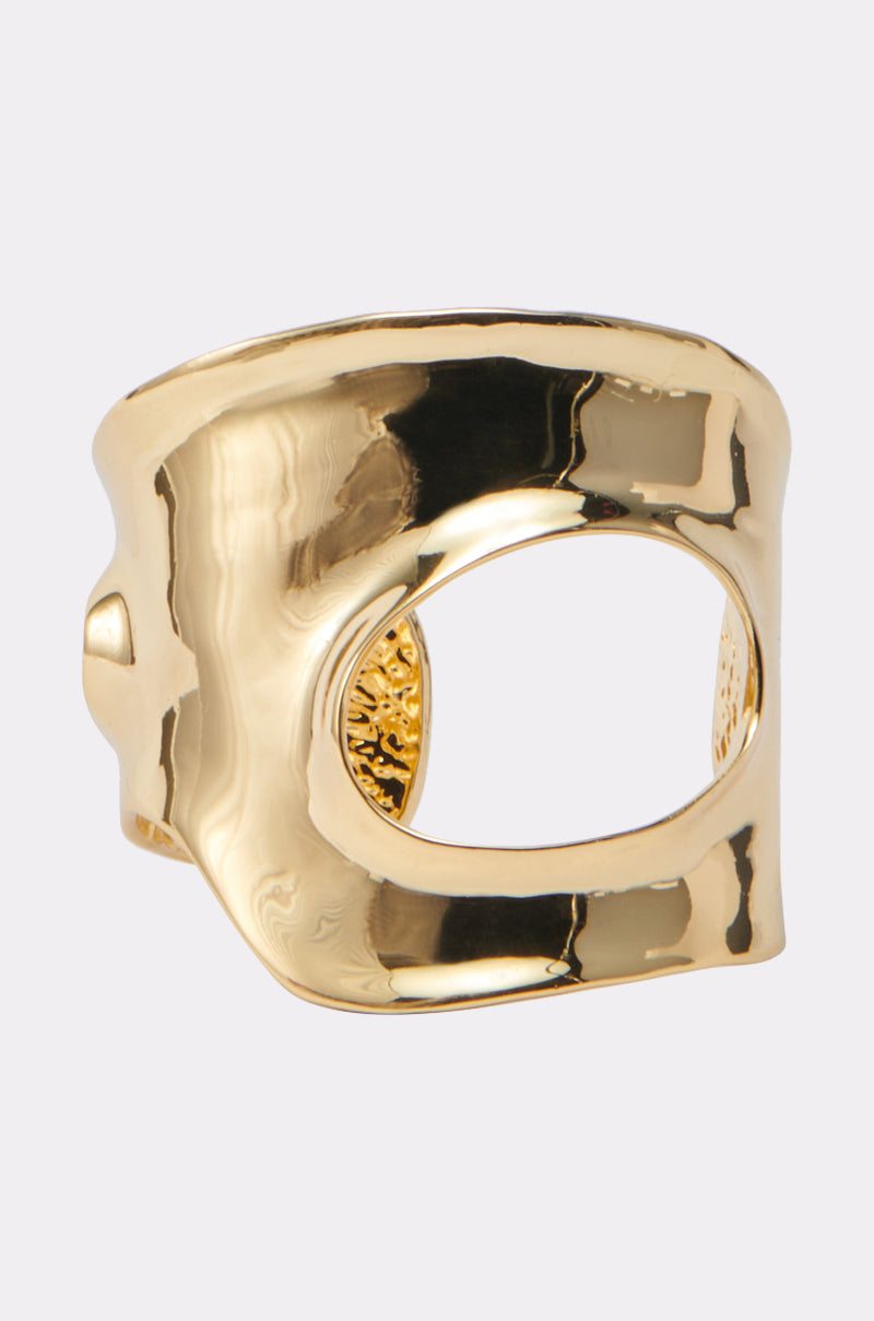 The MORE POWER TO YOU CUFF is a wide, faux gold metallic cuff by AKIRA Label, featuring an irregular, organic shape with a large asymmetrical cutout in the center, shown against a plain white background.