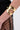 A close-up of a person's arm wearing the MORE POWER TO YOU CUFF from AKIRA Label, a faux gold metallic cuff with an open cut-out design. The person is dressed in black sheer fabric featuring a dotted pattern.