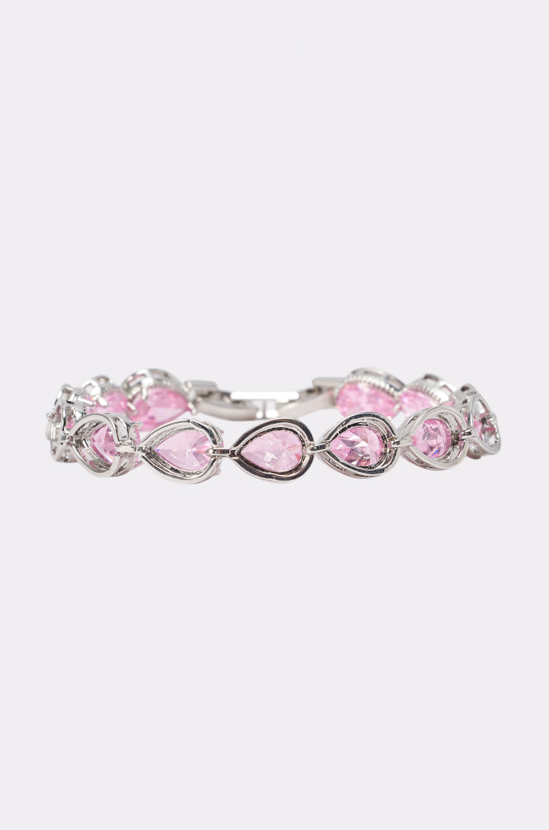 The GEORGINA BRACELET is a silver accessory with teardrop-shaped pink cubic zirconia stones in an open, interwoven design, shown on a plain light background—ideal for wearing as a wedding guest.