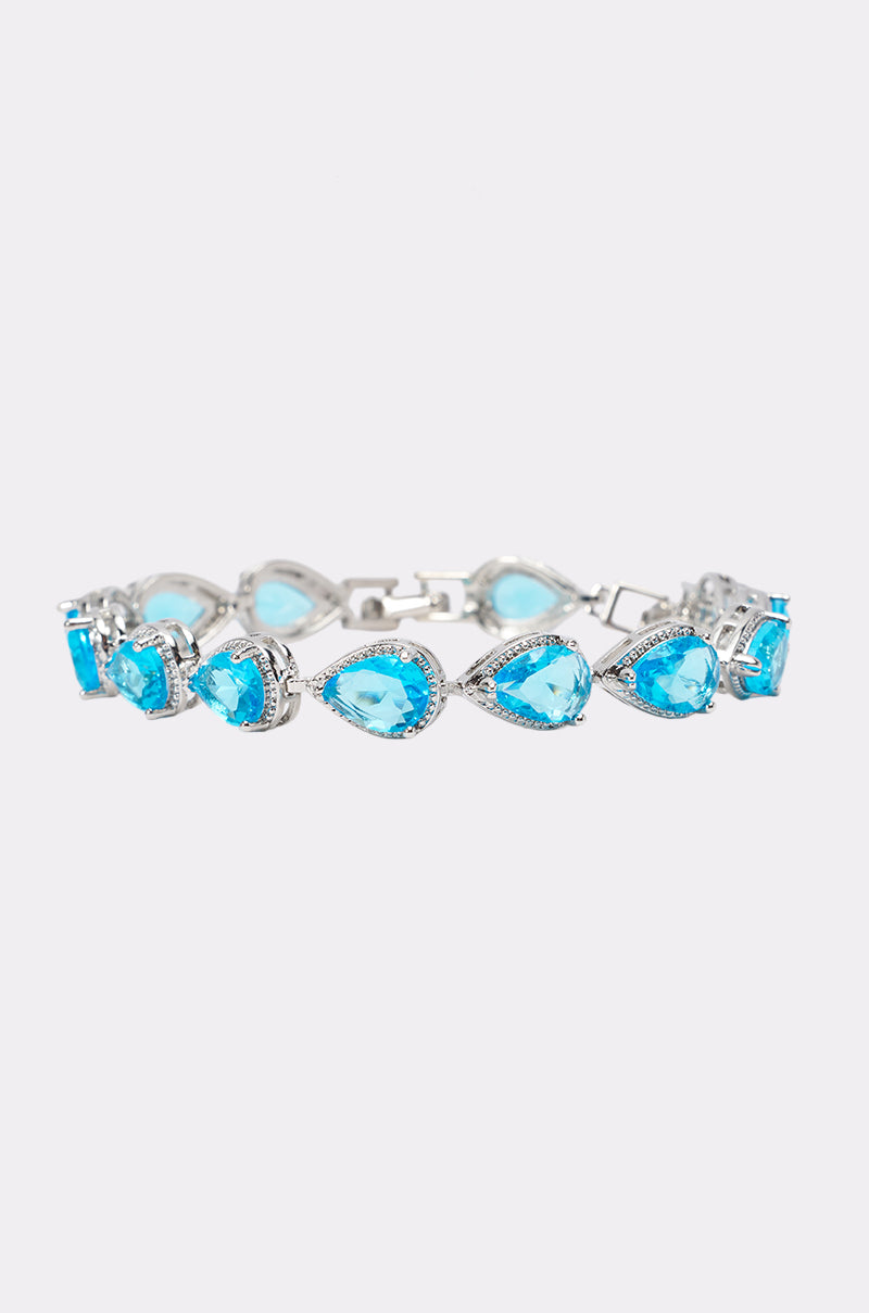 The AQUA CZ BRACELET features a striking blue teardrop crystal with silver accents, each gem encircled by sparkling cubic zirconia—an elegant choice for wedding guests.