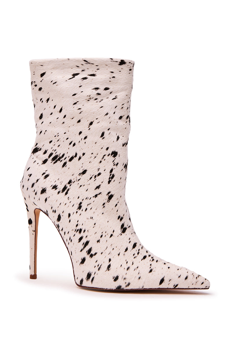The AZALEA WANG TYELOR WHITE BLACK PONY HAIR BOOTIE features a high heel, pointed toe, and sleek fitted design with white pony hair and black speckles for a dalmatian-inspired look. Thin stiletto heel completes the style.