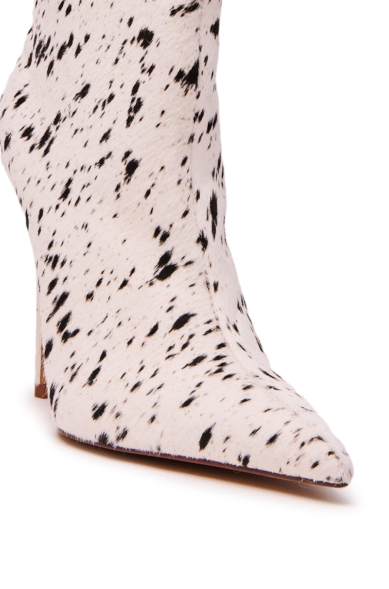 The AZALEA WANG TYELOR White Black Pony Hair Bootie features a pointed toe and dalmatian-inspired spots on a white base, shown against a white background.