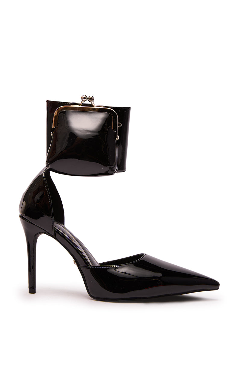 The AZALEA WANG TZIVA BLACK COIN PURSE PUMP features a pointed toe, unique ankle strap with small coin purse, shiny faux patent leather, and sleek stiletto heel, all showcased against a plain white background.