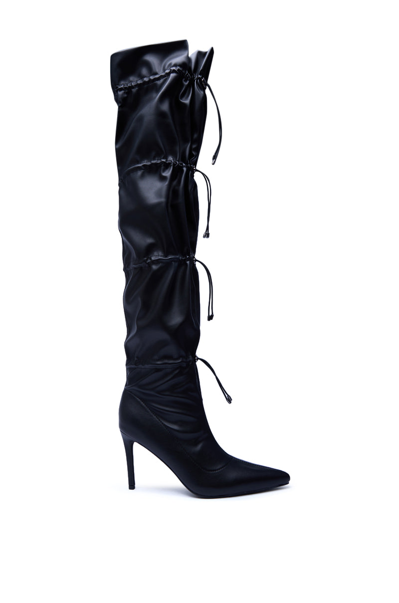 The AZALEA WANG ULVI BLACK CINCHED STILETTO BOOT is a single knee-high, pointed-toe stiletto crafted from sleek faux leather with a ruched shaft and three adjustable drawstring ties along the leg.