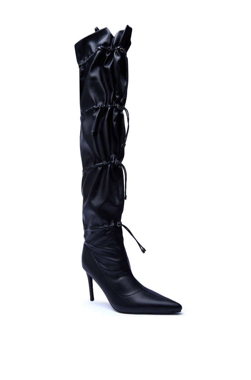 The AZALEA WANG ULVI BLACK CINCHED STILETO BOOT is a black, knee-high faux leather boot with a pointed toe, high heel, ruched shaft, and multiple drawstring ties for a bold style statement.