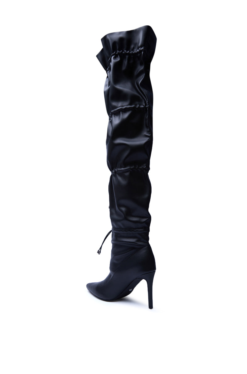 The AZALEA WANG ULVI BLACK CINCHED STILETTO BOOT features a pointed toe and ruched satin-like material, showcased solo against a plain white background.