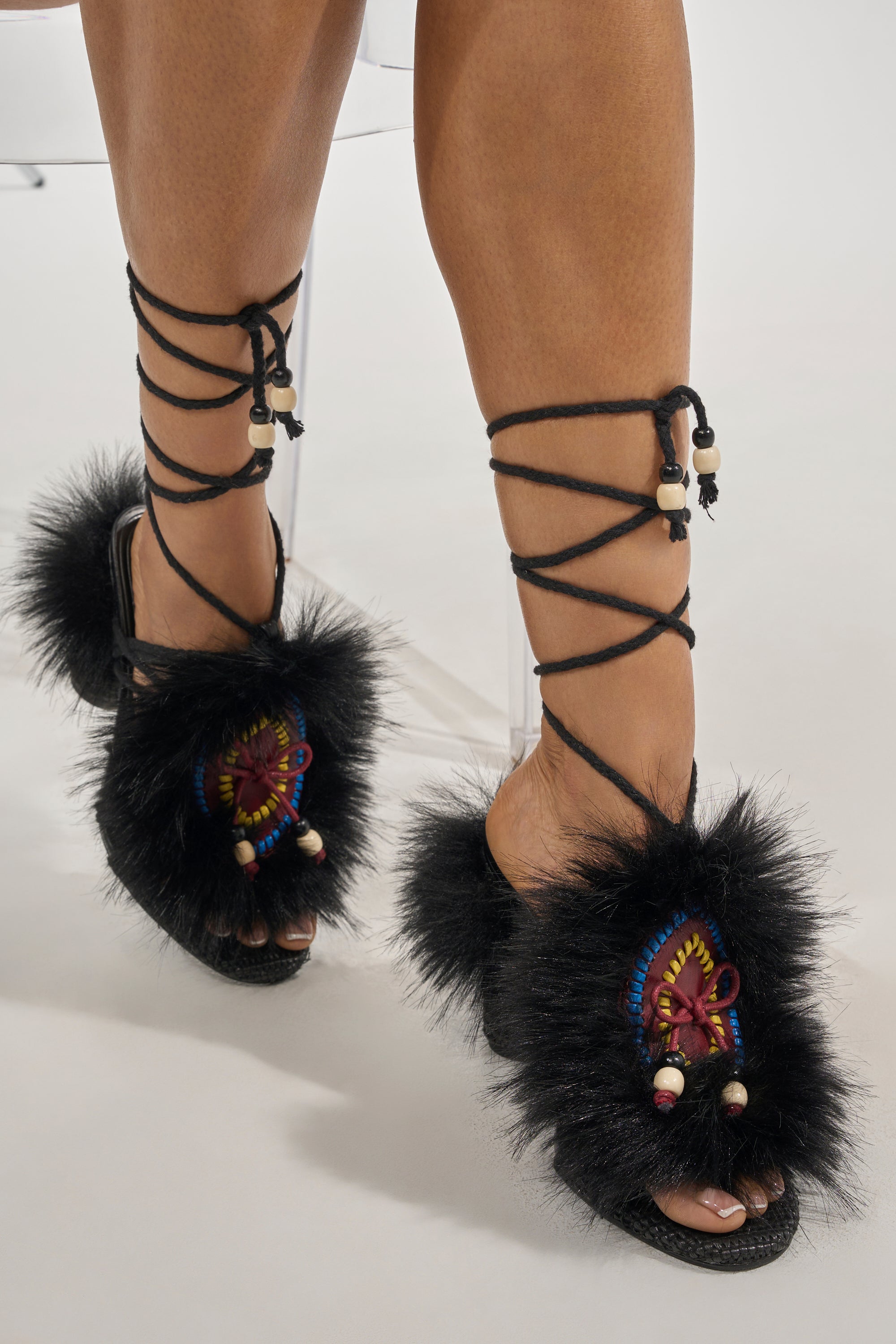The AKIRA GOLD UMIKA BLACK FUR BLOCK SANDAL features black faux fur, colorful embroidery, beaded accents, and lace-up ankle straps for a stylish boho-chic look. 6