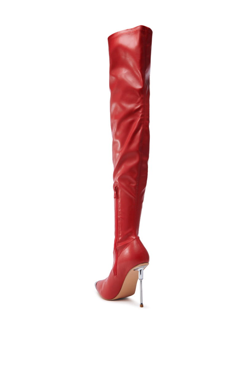 The UNA RED STILETTO BOOT, made from sleek faux leather, boasts a knee-high silhouette with a sharp pointed toe and high silver stiletto heel. The design stands out elegantly against a crisp white background.