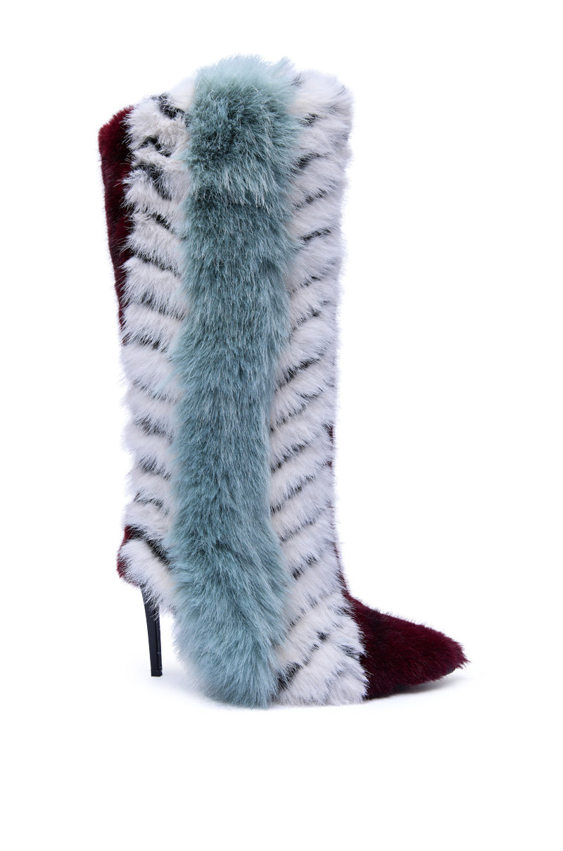 The AZALEA WANG UPSELLA BLUE MULTI STILETTO BOOT is a knee-high, pointed-toe faux fur boot in bold colors—white with black stripes, burgundy, and a striking vertical blue-green stripe.