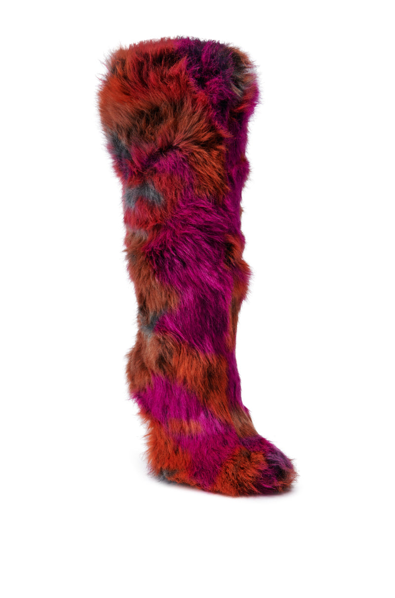 The AZALEA WANG UPSETTER ORANGE MULTI FUZZY KNEE HIGH BOOT features a vibrant mix of purple, red, and orange hues on a plain white background. This tall boot is covered in fuzzy faux fur that extends from the knee down, offering a soft and lively texture.