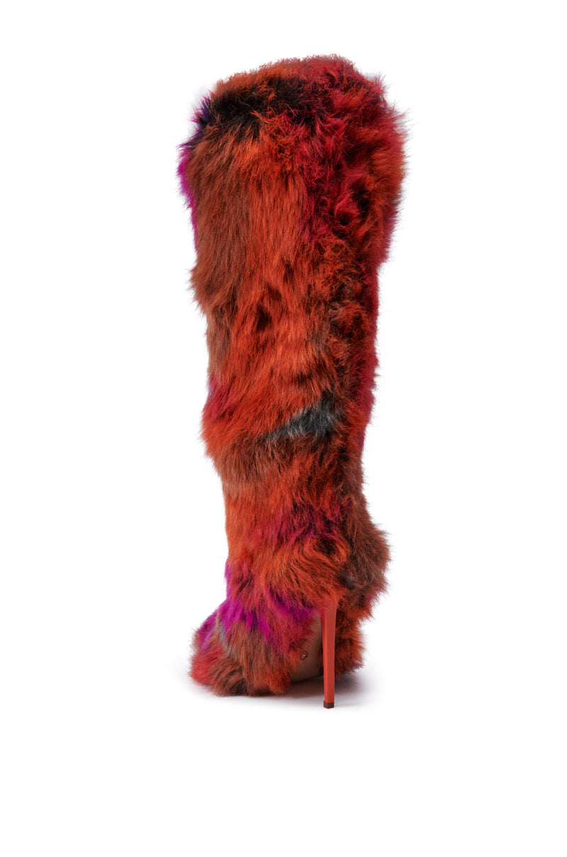 The AZALEA WANG UPSETTER ORANGE MULTI FUZZY KNEE HIGH BOOT features an array of vibrant multicolored faux fur in shades of red, orange, brown, and purple. This eye-catching boot stands out with its pointed toe and sleek stiletto heel, all beautifully contrasted against a plain white background.