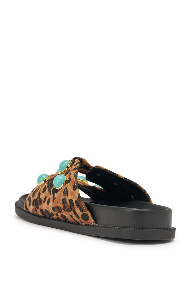 The AZALEA WANG UZUMATI Leopard Slip On Sandal features a calf-hair texture upper, bold turquoise stone embellishments, and a thick black sole. Displayed from a rear side angle against a white background. 6
