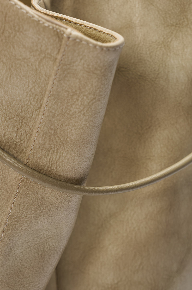 Close-up of a textured beige leather handbag with visible stitching, styled effortlessly with the AZALEA WANG VAILEN GREY OPEN TOE SLOUCHY BOOTIE. 11