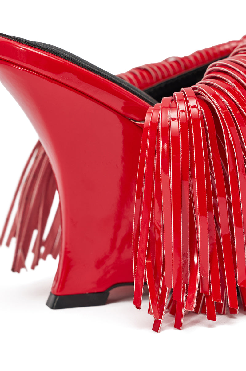 Close-up of the AZALEA WANG VAILYN RED FRINGE PU WEDGE SANDAL, showcasing a cherry-red hue with long, glossy red fringe on the upper and side, a sculpted wedge heel, and black sole against a white background. 6
