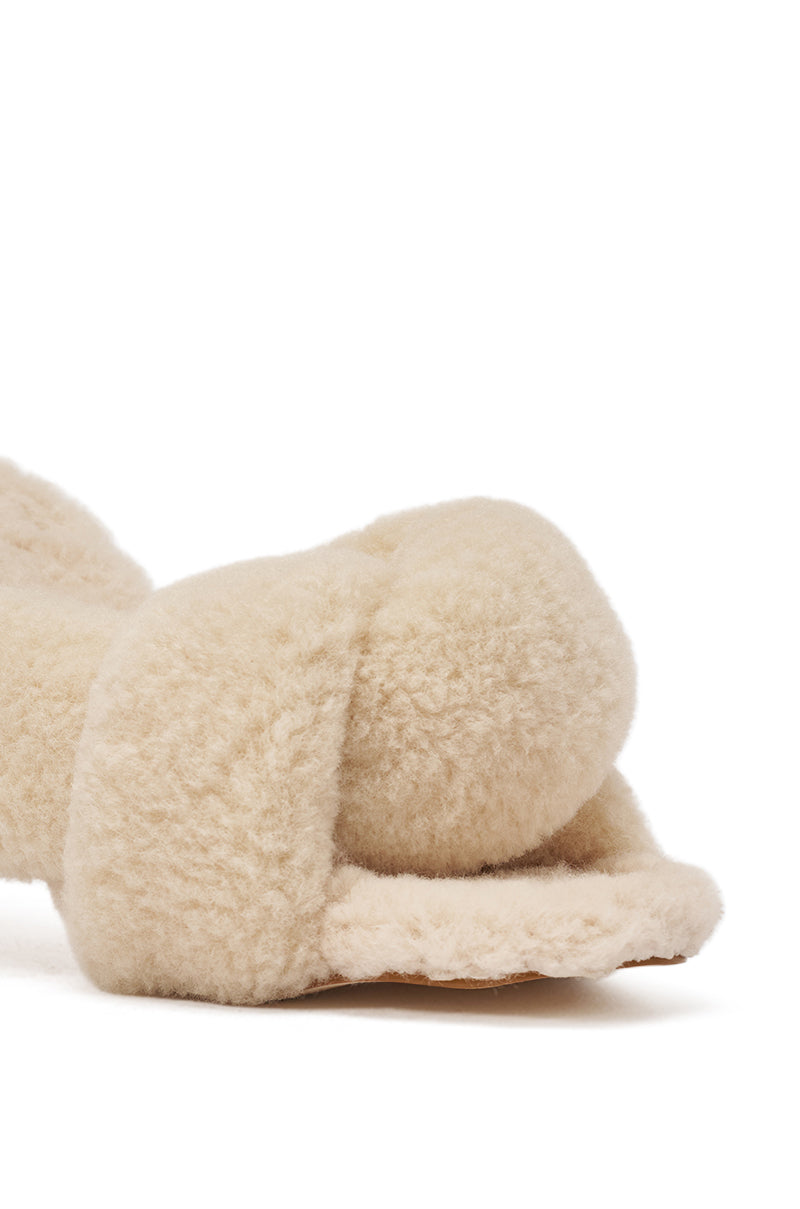 A close-up of the AZALEA WANG VALE IVORY SHERPA LOW HEEL MULE SANDAL shows its beige, plush teddy-textured crisscross straps and soft sherpa material against a white background. 6