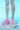 A person wearing white stockings is set against a blue background, highlighting the AZALEA WANG VALENCIANA PINK CHUNKY SANDAL, featuring a faux fur upper and a light blue fluffy platform.