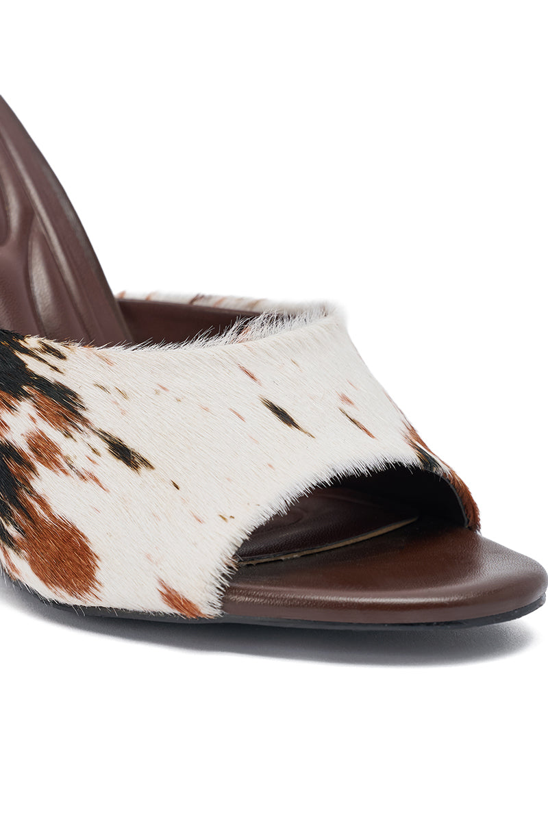 The AZALEA WANG VASA COW PRINT OPEN TOE SANDAL features a wide, genuine calf hair strap in white, brown, and black cow print with an open toe design and a smooth brown footbed.