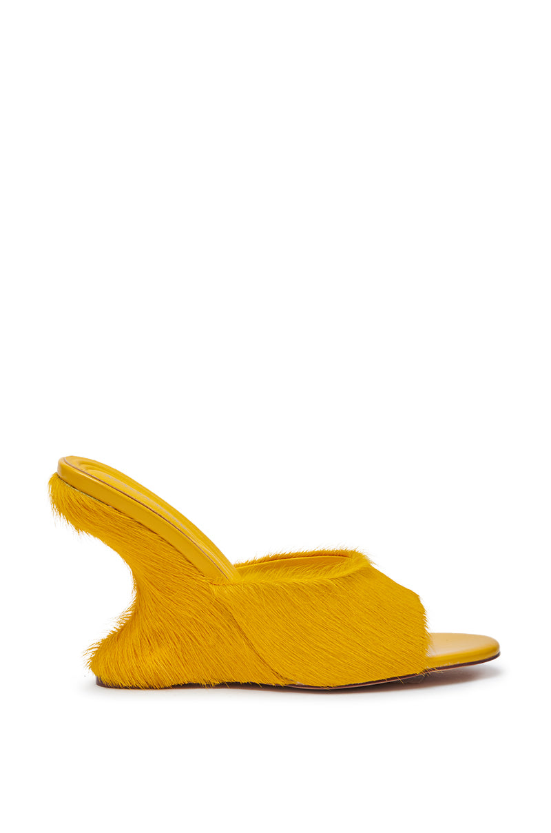 The AZALEA WANG VASA MUSTARD OPEN TOE SANDAL features faux fur with a fringe-like texture, wedge heel, sculpted curved sole, and open toe for a unique look.