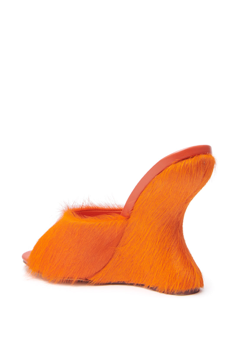 The AZALEA WANG VASA ORANGE FURRY WEDGE SANDAL is a high-heeled mule with bright orange faux pony hair, an open almond toe, and an exaggerated curvy wedge heel. 6