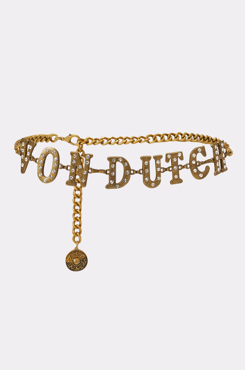 Elevate your festival style with the VON DUTCH RHINESTONE CHAIN BELT, featuring gold rhinestone letters and an adjustable dangling chain with a round medallion charm. 1
