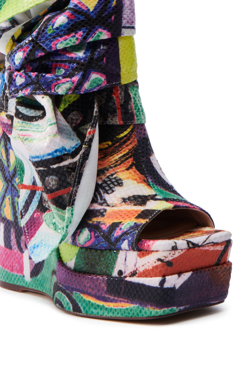 The AZALEA WANG VENEZIO MULTI BOOTIE is a vibrant platform shoe featuring an abstract technicolor print, open toe design, and chunky wedge heel with swirls and splashes of various colors for a bold, artistic look.