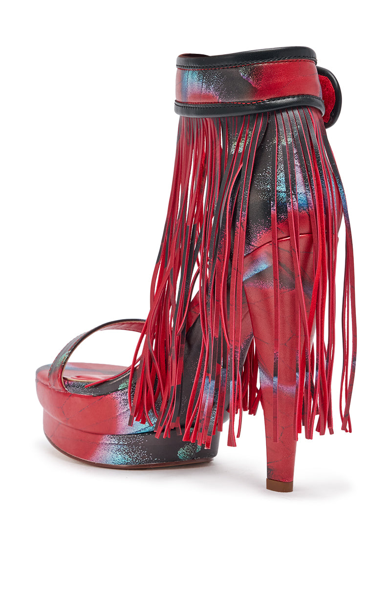 The AKIRA GOLD PRINTED PU FRINGE STILETTO SANDAL features a platform stiletto heel, ankle strap, gold printed PU material, and long fringe detailing around the ankle for a bold festival look. 5