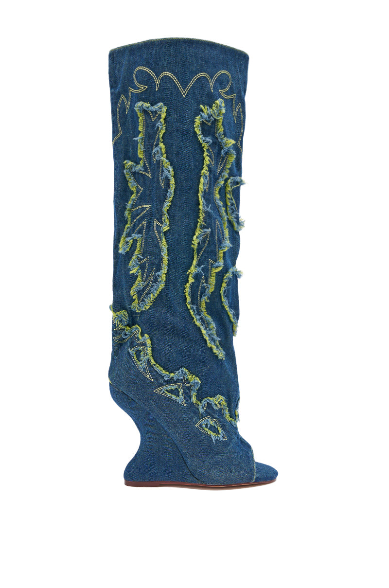 The AZALEA WANG VIANCA GREEN MULTI DENIM WEDGE BOOT is a knee-high, blue denim boot with exposed greenish-yellow stitching, frayed jagged appliqué details, a unique curved wedge heel, and an open toe for a modern western look.