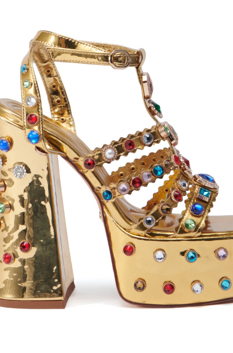 The AZALEA WANG VIANNI GOLD CHUNKY SANDAL features a shiny gold finish and a thick platform. It has multiple straps enhanced with multicolor gemstone embellishments in red, blue, green, and clear stones, providing a luxurious and vibrant appearance while ensuring comfort with its cushioned insole.