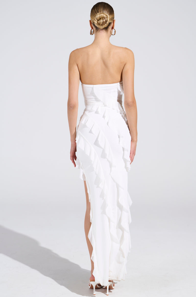 A person with their hair in a bun is showcasing the ELLA MESH TUBE DRESS IN WHITE against a white background. The strapless silhouette and elegant ruffle detailing are highlighted from the back view.