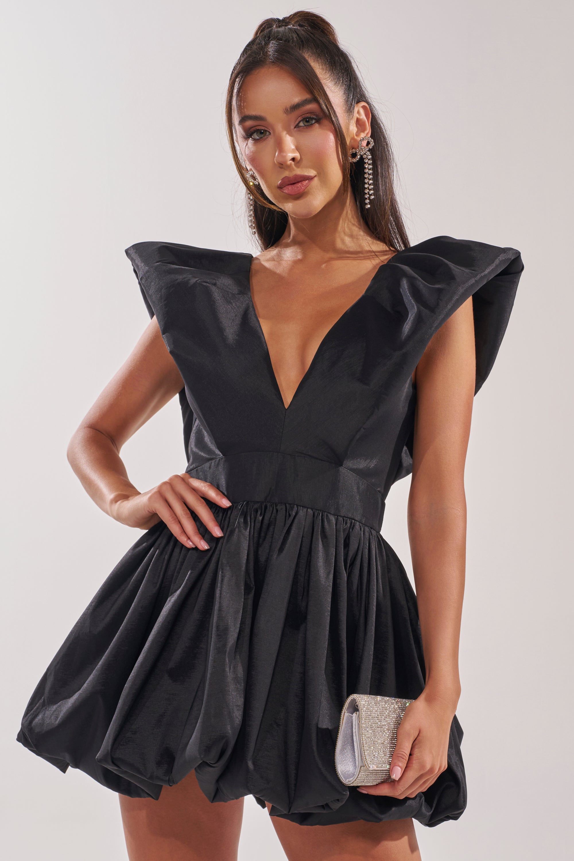 Wearing the ONCE UPON A DREAM WOVEN MINI DRESS IN BLACK, she stuns with its plunging v-neckline, structured shoulders, and voluminous skirt. She accessorizes with a sparkling silver clutch, styled hair, and statement earrings.