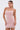 A woman with long, straight hair wears the PEARL QUEEN MINI DRESS—a light pink party dress featuring textured beading and thin straps. She stands against a plain white background with a neutral expression.