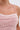 Close-up of a person wearing the PEARL QUEEN MINI DRESS, a pink party dress with thin straps, adorned with white and silver sequins and beads for a textured, sparkly effect. The background is plain and light-colored.