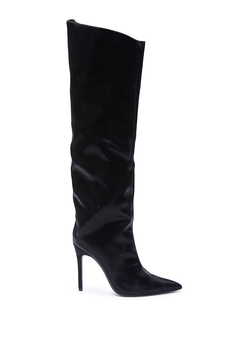 The AZALEA WANG VIETTA BLACK LIQUID LUXE STILETTO BOOT features a pointed toe, slouchy faux leather knee-high shaft, and high stiletto heel, shown in profile against a white background.