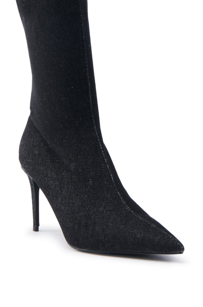 Close-up of the AZALEA WANG VILLAREAL DENIM BOOT WITH TIES, a black knee-high boot featuring a pointed toe and textured fabric finish, complemented by a slim stiletto heel for a sleek and elegant look.