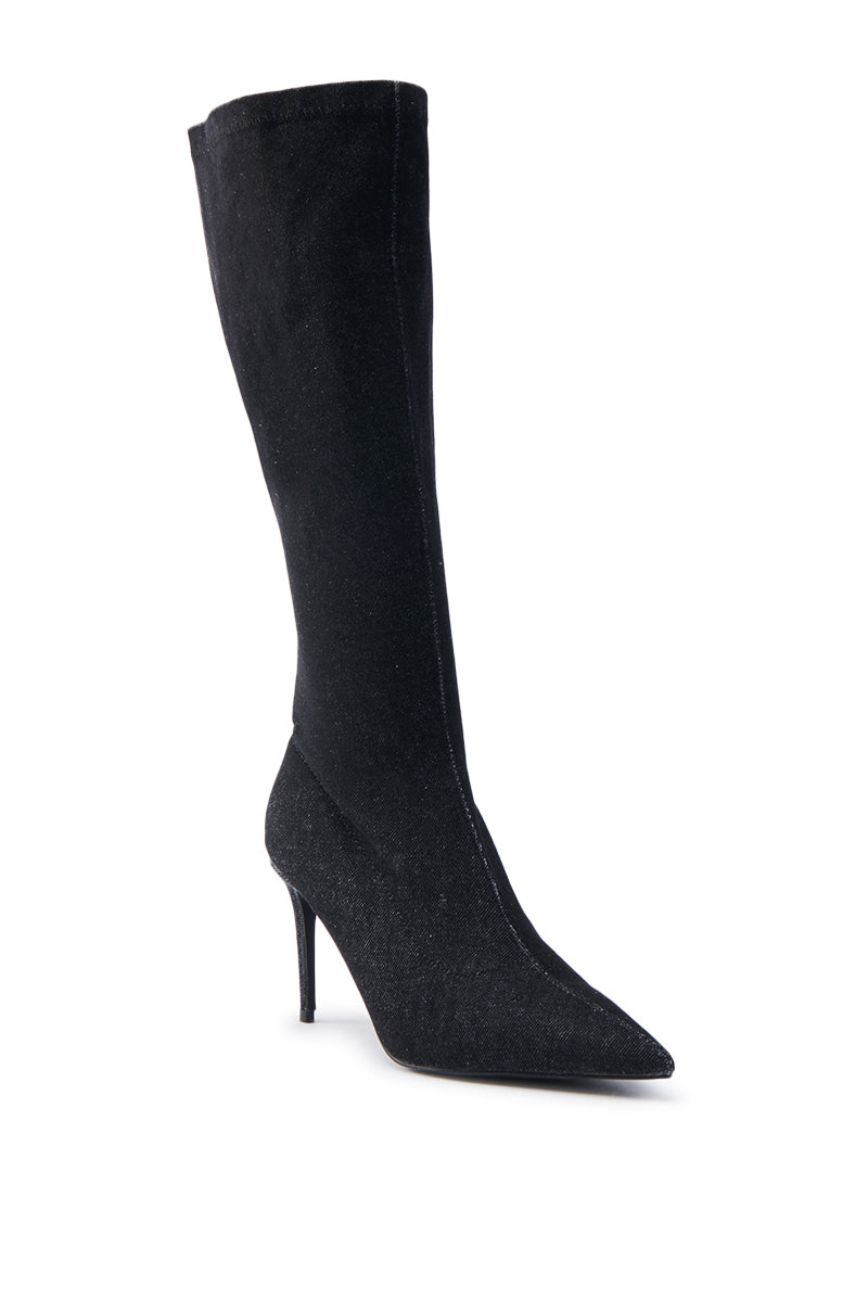 A single knee-high boot from AZALEA WANG, showcased against a white background. This elegant black denim footwear has a pointed toe and towering stiletto heel, featuring a streamlined design with ties for added sophistication.