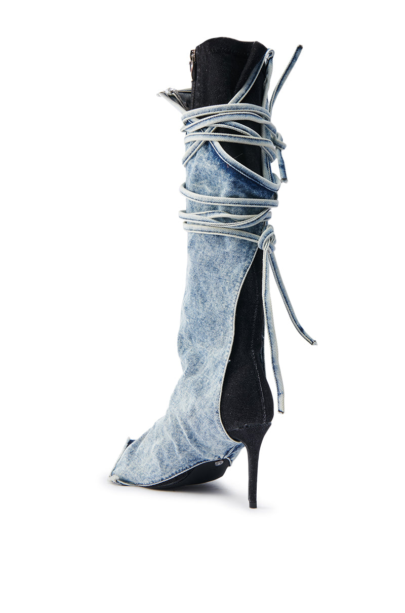 The AZALEA WANG VILLAREAL DENIM BOOT WITH TIES features a knee-high stiletto design with light blue denim fabric wrapping around the shaft, tied for a layered look. Its pointed toe and slender heel enhance its unique and fashionable elegance.
