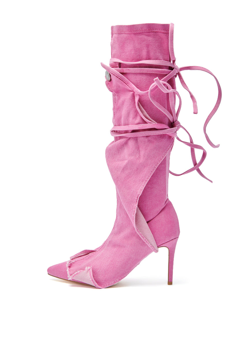 The AZALEA WANG VILLAREAL PINK STRAPPY BOOT is a pink high-heeled, pointed-toe boot with open side seams, long wraparound laces, frayed edges, and a dramatic stiletto heel for a bold deconstructed look.