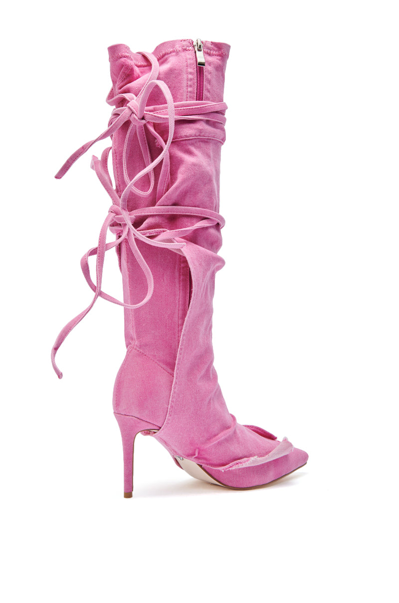 The AZALEA WANG VILLAREAL PINK STRAPPY BOOT is a knee-high, pink denim boot featuring a stiletto heel, open toe, zip closure, and wrap-around laces for added style and texture.
