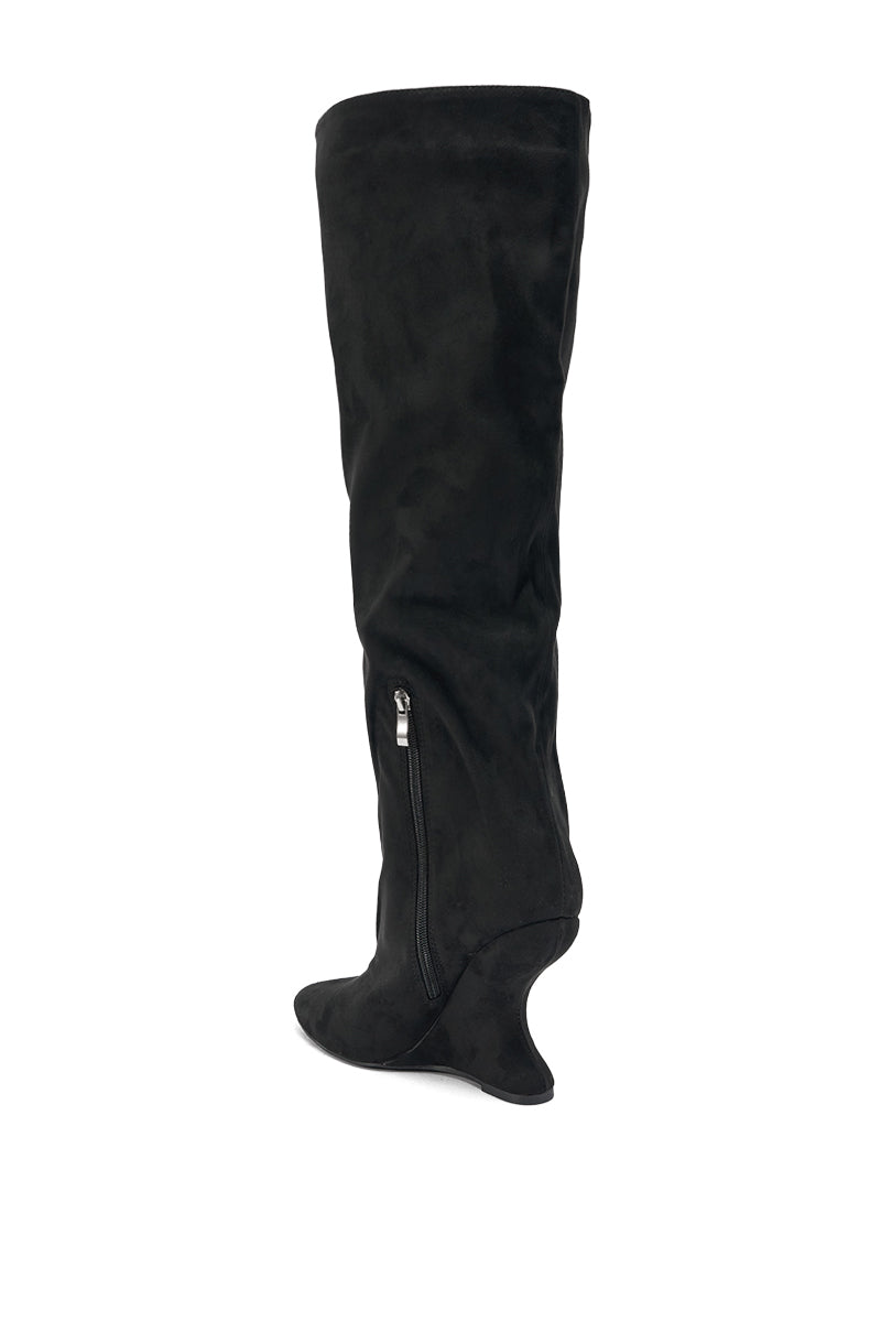 The AZALEA WANG VINCE BLACK FAUX SUEDE WEDGE BOOT features knee-high black faux suede with a pointed toe, side zipper, and unique sculpted curved wedge heel, standing out against a white background.