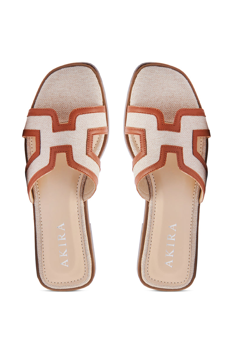 The AKIRA VITTORIA BEIGE SANDAL offers a stylish slip-on design with a woven textile in beige and brown tones, featuring open square toes and a cream-colored insole with "AKIRA" printed in silver letters.