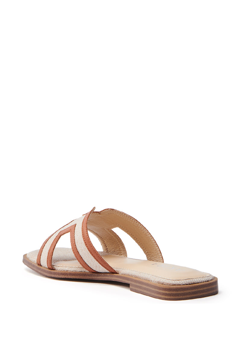 The AKIRA VITTORIA BEIGE SANDAL features a beige and brown flat design with an open square toe and overlapping woven textile straps forming a geometric pattern. Its slightly elevated heel adds a casual yet stylish touch, making it ideal for any occasion.